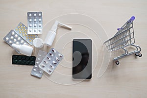 Online pharmacy concept. Buying medicine online over the phone. Delivery of pharmaceuticals. Mini trolley with different