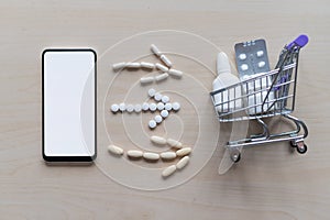 Online pharmacy concept with home delivery. Buying medicine online by phone. Mini trolley with different tablets, sprays