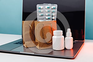 Online pharmacy concept. Paper bags with prescription drugs and pills and white conteiners on laptop