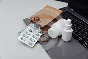 Online pharmacy concept. Pills and spray containers and buff paper bags on the laptop