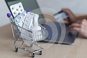 Online pharmacy concept. A woman holds a credit card in her hands and buys pills online. A girl makes an online purchase