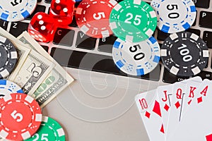 Online poker casino theme. Gambling chips with dice, playing cards, american dollars on laptop photo