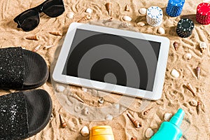 Online poker game on the beach with digital tablet and stacks of chips. Top view