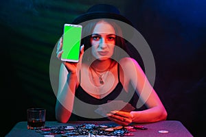 online poker player with a smartphone at a casino table with cards and chips