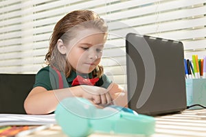 Online remote learning. School kids with computer having video conference chat with teacher in class. Child studying at