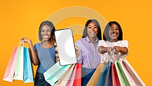 Online Sales. Thre Black Females With Bright Shopping Bags Showing Blank Smartphone
