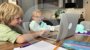 Online school class, siblings pupils boy and girl learning together remotely online at home, looking to laptop, speaking