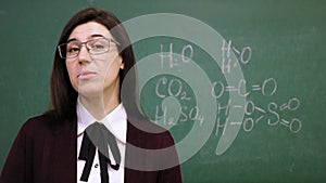 Online schooling. Female teacher is holding online chemistry lesson in school class. background of blackboard with