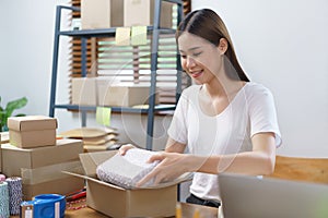 Online selling concept, Asian business women packing product into parcel box for prepare delivery
