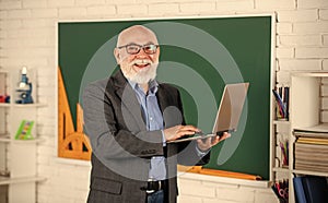 Online service. Videoconferencing keeps homebound students connected. Senior intelligent man teacher use laptop. Distant photo