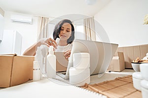 Online shop female employee packing ordered items for shipping