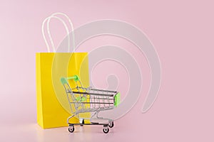 online shopping background, shopping bag and supermarket cart on pink background, sale and discount