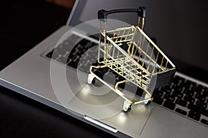 Online shopping bank card nearby a laptop and mini shopping cart