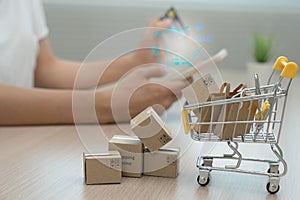 Online shopping-boxes or parcels are placed on the table and shopping carts. Blurred background, woman use credit card to make