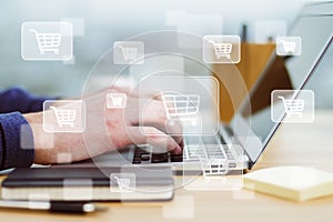 Online shopping concept with digital supermarket trolley icons on man hands typing on keyboard background
