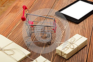 Online shopping concept - Empty Shopping Cart, laptop and tablet pc, gift box on rustic wooden background