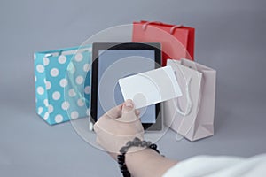Online shopping concept. A girl holds a credit card in her hands, against the background of a tablet mockup with a white screen
