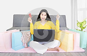 Online shopping concept. Happy young asian woman with laptop and credit card making online shopping and many shopping bag ,e-