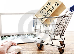Online shopping concept with miniature shopping cart and laptop computer on table
