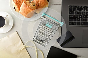 Online shopping concept with shopping cart devices card and breakfast