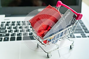 Online shopping concept. Shopping cart, small box, laptop, credit card on the desk. close up, copy space