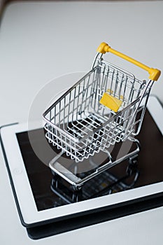 Online shopping concept. Shopping cart  small boxes  laptop on the desk photo