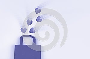 Online shopping concept. Top view of gift bag and paper hearts on very peri background with ripple effect, copy