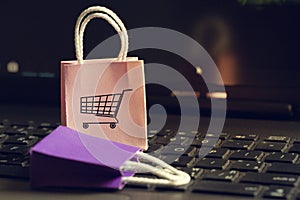 Online shopping concept: Two paper shopping bags on notebook keyboard. E-commerce is the purchase of products and services on the