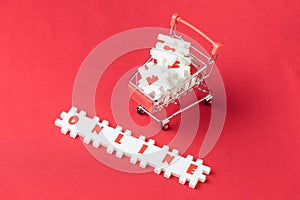 Online shopping concept, white puzzle jigsaws with alphabets building the word Online with shopping cart or trolley on red fabric