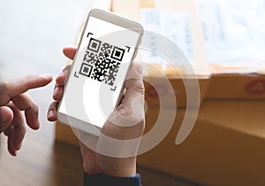 Online shopping concepts with youngman using smartphone with qr code on product package box