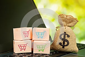 Online shopping or delivery service concept cardboard boxes with trolley sign and sack bag on laptop keyboard service