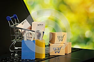Online shopping or delivery service concept shopping bag with cardboard boxes in trolley on laptop keyboard service