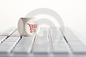 Online shopping and e-commerce concept with shopping cart icon on wooden cube on computer keyboard.