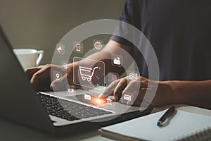 Online shopping and e-commerce concept. Young man using laptop computer with shopping cart icon