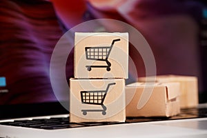 Online shopping . ecommerce and delivery service concept : Paper cartons with a cart or trolley logo on a laptop