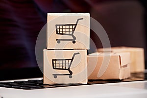 Online shopping . ecommerce and delivery service concept : Paper cartons with a cart or trolley logo on a laptop