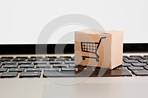 Online shopping . ecommerce and delivery service concept : Paper cartons with a cart or trolley logo on a laptop