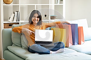 Online Shopping. Happy Arab Woman Pointing At Laptop With Blank Screen