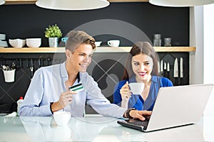 Online Shopping. Happy smiling couple using credit card to shop online at home.