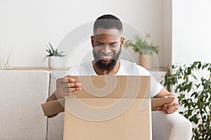 Online shopping at home. Smiling guy unpack delivery