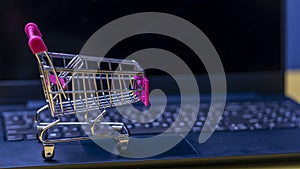 Online shopping. A laptop and mini shopping cart and gadgets