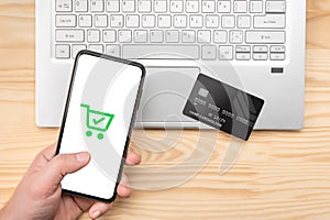 Online shopping, phone laptop and credit card. Top view man at wooden desk with mockup phone , credit card and laptop