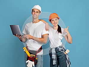 Online Shopping For Repair. Couple In Hardhats Holding Laptop Showing Thumb Up