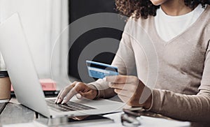 Online shopping. Young woman holding credit card and using laptop at home