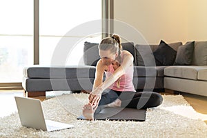 Online sport fitness yoga training. woman doing exercises on yoga mat opposite laptop. training at home