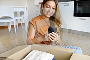 Online store selling clothes on website working on smartphone ecommerce business from home. Woman packing clothing purchase in