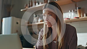 Online student drinking coffee at home kitchen close up. Woman looking laptop