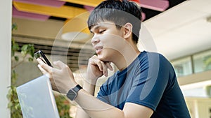 Online studying concept the young man in deep blue T-shirt and black watch using his smartphone to call his friends because they