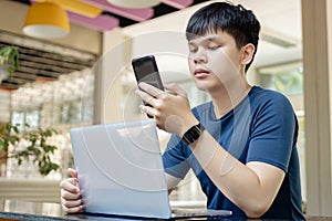 Online studying concept the young man in deep blue T-shirt and black watch using his smartphone to call his friends because they