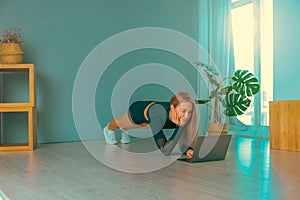 Online trainer. On-line sports. fitness and healthy lifestyle concept. Woman with laptop computer doing plank exercise